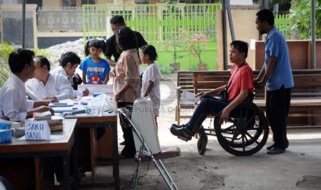  Warga Jakarta penyandang disabilitas tuna daksa dengan bantuan petugas, mengantre untuk menggunakan hak suaranya.  (Aditya Pradana Putra/Republika)