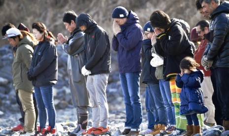 Warga Jepang mengenang korban tsunami tujuh tahun lalu di pinggir pantai Kesenuma di utara Jepang, Ahad (11/3).