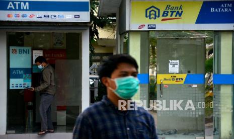 Warga keluar dari mesin Anjungan Tunai Mandiri (ATM) usai melakukan transaksi. Memasuki PPKM darurat, OJK menyatakan tetap  melakukan pengawasan dan pemeriksaan sektor jasa keuangan. 