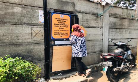 Warga Kelurahan Menteng Atas, Kecamatan Setiabudi berbelanja dari balik pagar setelah akses jalan kecil ditutup oleh pengelola Apartemen Taman Rasuna.