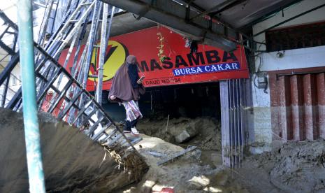 Warga korban banjir bandang melihat kondisi tokonya yang hancur diterjang material lumpur di Masamba, Kabupaten Luwu Utara, Sulawesi Selatan. 