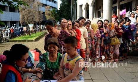 Warga korban banjir mengantri memeriksa kesehatan di lokasi pengungsian di Masjid Univesitas Borobudur, Jakarta,Rabu (22/2).