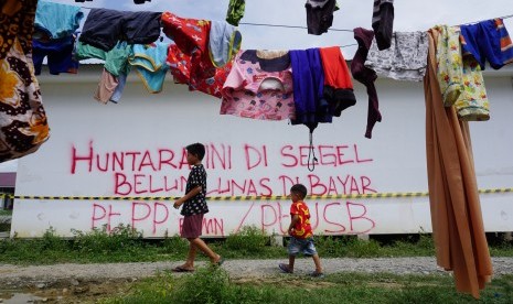 Warga korban bencana gempa dan tsunami berjalan di sekitar Hunian sementara (Huntara) Mamboro yang dipasangi garis segel, di Palu, Sulawesi Tengah, Kamis (16/5/2019). 