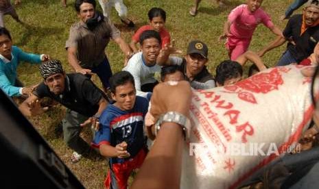 Warga korban gempa berebut pembagian logistik yang diangkut menggunakan helikopter di Kecamatan Sirenja, Palu, Sulawesi Tengah, Ahad (7/10). 