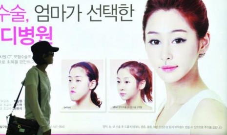 Warga Korea Selatan berjalan di depan sebuah iklan operasi rahang ganda