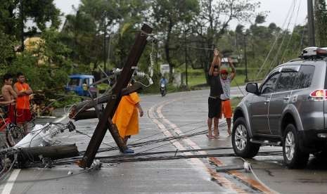 Warga Kota Lal-lo, Provinsi Cagayan, Filipina, berusaha menyingkirkan tiang listrik yang roboh menghalangi jalan akibat Topan Mangkhut, Sabtu (15/9).