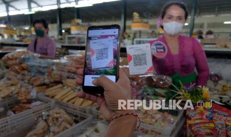 Warga melakukan pembayaran menggunakan fitur pemindai QRIS di Pasar Nyanggelan, Desa Panjer, Denpasar, Bali, Jumat (1/4/2022). Bank Indonesia dan Bank Negara Indonesia (BNI) bekerja sama dengan Pemerintah Kota Denpasar dalam menerapkan digitalisasi pembayaran pada program Sehat, Inovatif, dan Aman Pakai (SIAP) QRIS di pasar tradisional untuk meningkatkan pelayanan publik dan optimalisasi transaksi belanja secara non tunai berbasis digital sehingga mencegah peredaran uang palsu serta mengurangi kontak fisik antara pedagang dan konsumen dalam pencegahan penyebaran COVID-19.