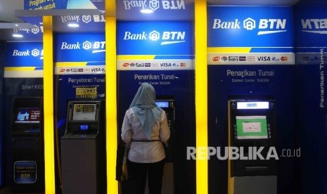 Warga melakukan transaksi menggunakan mesin ATM Bank BTN di Jakarta, Ahad (31/7). (Republika/ Agung Supriyanto)