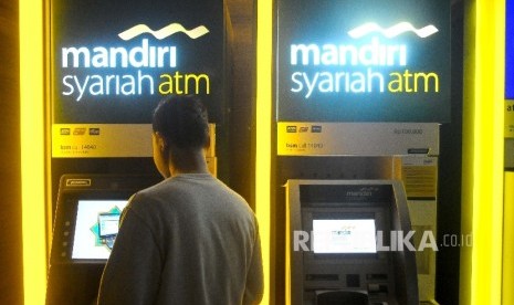 Warga melakukan transaksi menggunakan mesin ATM Bank Mandiri Syariah, Jakarta, Ahad (12/3).