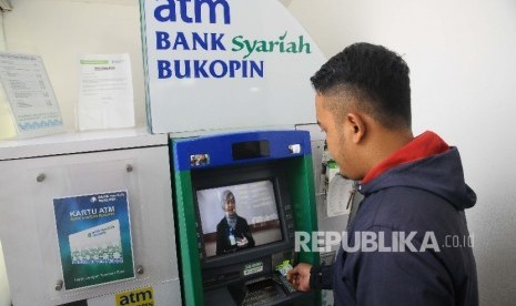  Warga melakukan transaksi menggunakan mesin ATM di Bank Syariah Bukopin, Jakarta, Ahad (5/3).