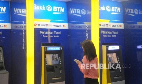 Warga melakukan transaksi menggunakan mesin ATM di bank BTN, Jakarta, Ahad (5/2). 