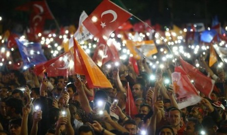 Warga melambai-lambaikan bendera Turki dan memegang telepon seluler ketika mereka berkumpul untuk menyambut Presiden Turki dan pemimpin Partai Keadilan dan Pembangunan (AK Party) Recep Tayyip Erdogan dari balkon markas Partai AK yang berkuasa menyusul keberhasilan pemilihannya dalam pemilihan presiden dan parlemen di Ankara, Turki, Senin (25/6).