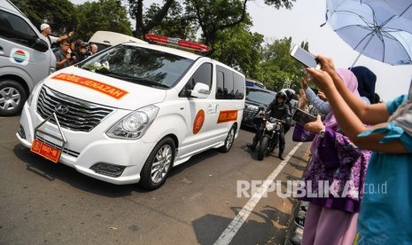 Warga melambaikan tangan ke mobil jenazah yang membawa almarhum Presiden ke-3 Republik Indonesia BJ Habibie saat berjalan menuju Taman Makam Pahlawan Nasional Utama Kalibata dari rumah duka di kawasan Patra Kuningan, Jakarta, Kamis (12/9/2019).