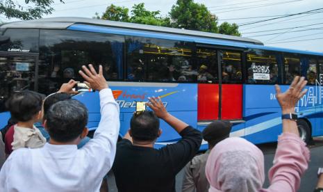 Warga melambaikan tangan kepada jamaah calon haji yang berada dalam bus saat pelepasan jamaah calon haji kelompok terbang (kloter) pertama embarkasi Medan di Asrama Haji Medan, Sumatera Utara, Sabtu (11/6/2022). Sebanyak 391 jamaah calon haji asal Kota Medan, Kabupaten Mandailing Natal, Tapanuli Tengah dan Serdang Bedagai diberangkatkan menuju tanah suci Arab Saudi. 