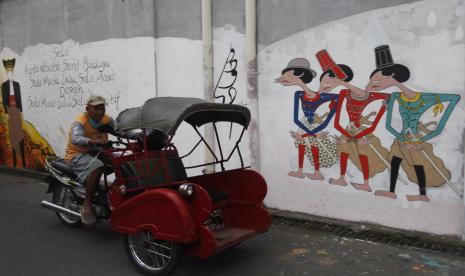 Warga melewati mural bergambar Wali Kota Solo Gibran Rakabuming Raka dan prajurit Keraton Kasunanan Surakarta Hadiningrat di Kampung Batik Laweyan Solo, Jawa Tengah, Senin (22/11/2021). Mural tersebut dibuat sebagai promosi wisata Kota Solo sekaligus menambah daya tarik bagi wisatawan berkunjung di Kampung Batik Laweyan.