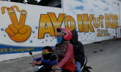 Warga melewati mural bertem Keluarga Berencana di Kampung Pucang Sawit, Solo Jawa Tengah, Senin (28/9/2020). 