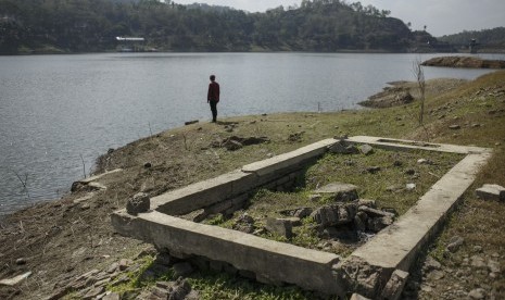 Warga melihat bekas makam yang terlihat saat air surut di Waduk Sermo, Kulonprogo, DI Yogyakarta, Selasa (16/7/2019).