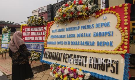 Warga melihat karangan bunga bertuliskan dukungan terhadap aparat untuk mengusut tuntas kasus dugaan korupsi di Dinas Damkar Depok di Polrestro Depok, Depok, Jawa Barat, Senin (19/4). Karangan bunga tersebut sebagai dukungan kepada Kepolisian Kota Depok dan salah satu petugas Pemadam Kebakaran Kota Depok yang menyuarakan dugaan korupsi di Dinas Damkar Depok. 