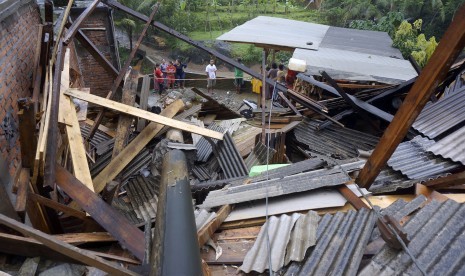 Warga melihat kondisi bangunan permukiman yang ambruk tertimpa tiang listrik akibat longsor di Munjungan, Trenggalek, Jawa Timur. 