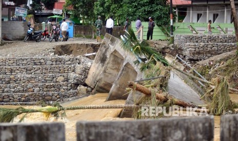 Warga melihat kondisi jembatan rusak akibat banjir bandang di Nagari Pakan Raba