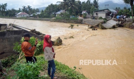 Warga melihat kondisi jembatan rusak akibat banjir bandang di Nagari Pakan Raba