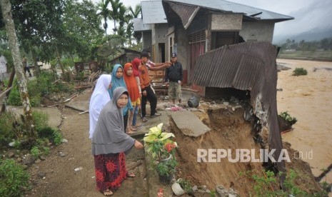 Warga melihat kondisi rumah yang rusak akibat banjir bandang di Nagari Pakan Raba