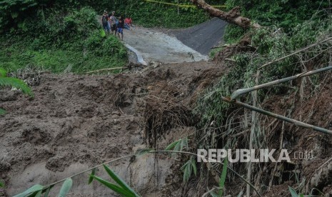 Warga melihat material tanah longsor yang menimbun jalan di Desa Santanamekar, Kecamatan Cisayong, Kabupaten Tasikmalaya, Jawa barat, Jumat (28/2/2020). 