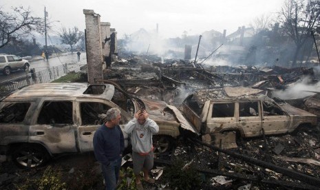 Warga melihat puing rumah yang terbakar akibat Badai Sandy di New York, Selasa (30/10).    (Keith Bedford/Reuters)