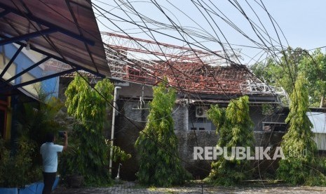 Warga melihat tower pemancar radio yang roboh menimpa rumah warga akibat angin kencang (ilustrasi)