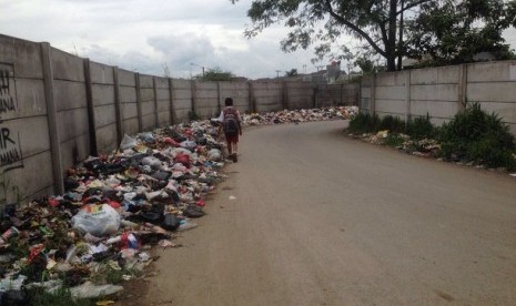 Warga melintas dekat tumpukan sampah di jalur masuk menuju Terminal Baleendah, Bojongsoang, Kabupaten Bandung, Selasa (1/2).