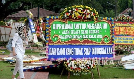 Warga melintas di antara karangan bunga yang ditujukan untuk Gubernur DKI Jakarta Basuki Tjahaja Purnama atau Ahok dan Wakil Gubernur Djarot Saiful Hidayat di halaman kantor Balai Kota Jakarta, Rabu (26/4) 