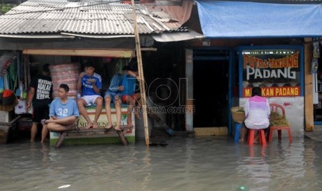   Warga melintas di atas genangan banjir rob sebagai dampak supermoon.  ( Rakhmawaty La'lang/Republika)