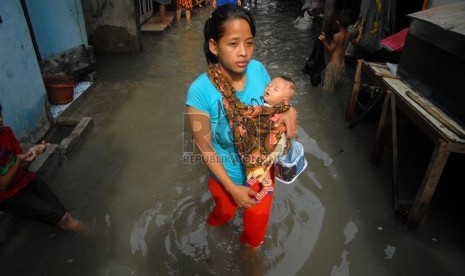   Warga melintas di atas genangan banjir ROB di kawasan Pluit, Jakarta Utara, Jumat (18/10).    ( Rakhmawaty La'lang/Republika)