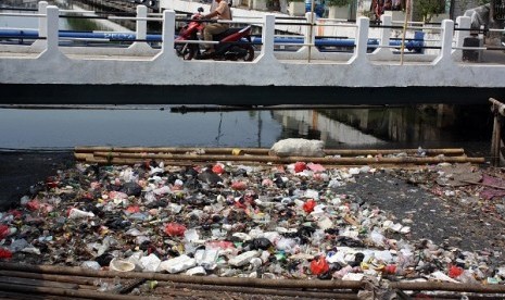 Warga melintas di atas jembatan kali item (Sunter) yang menumpuk banyak sampah, Serdang, Kemayoran, Jakarta, Rabu (16/10).