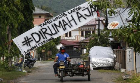 Warga melintas di bawah spanduk yang menyarankan orang untuk tetap di rumah selama pandemi Covid-19. Gugus Tugas Percepatan Penanganan COVID-19 menyebutkan seluruh data terkait penyakit akibat virus SARS-CoV-2 itu akan berada dalam satu sistem yang lebih terbuka dan transparan karena Presiden Joko Widodo sudah menetapkan pandemi tersebut sebagai bencana nasional.