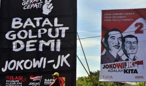 Warga melintas di dekat baliho kampanye anti Golput untuk Capres-Cawapres Joko Widodo-Jusuf Kalla di Makassar, Sulsel, Rabu (25/6). 