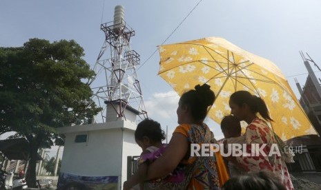 Warga melintas di dekat bangunan sirene sistem peringatan dini 