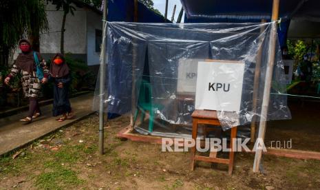 Warga melintas di dekat bilik suara khusus di TPS 02, Desa Pananjung, Kabupaten Pangandaran, Jawa Barat, Rabu (9/12/2020). Komisi Pemilihan Umum (KPU) menyediakan bilik khusus di luar TPS bagi pemilih yang suhunya di atas 37,3 derajat celcius. 