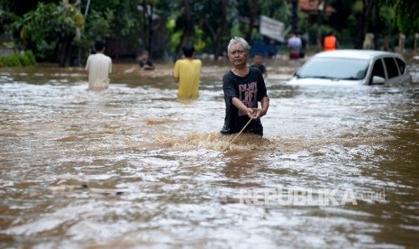  Warga melintas di dekat mobil yang terendam air luapan Sungai Ciliwung, Bukit Duri, Jakarta, Kamis (16/2). 