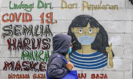 Warga melintas di dekat mural bertemakan Covid-19 di Petamburan, Jakarta, Rabu (21/7/2021). Protokol kesehatan merupakan kunci pengendalian pandemi Covid-19.