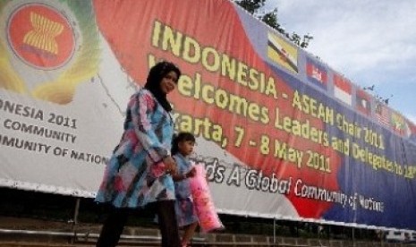 Warga melintas di depan baliho besar bertemakan penyelenggaraan Konferensi Tingkat Tinggi (KTT) ASEAN ke-18.