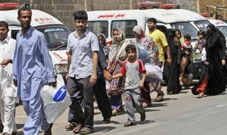 Warga melintas di depan mobil ambulans di kota Lyari, Pakistan, Ahad (29/4). (Ilustrasi)