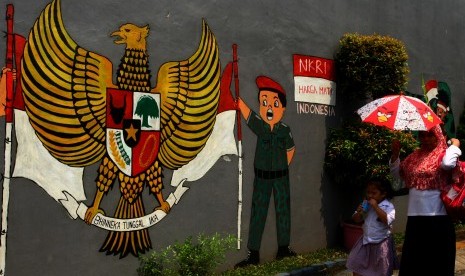 Terkikisnya nilai Pancasila dinilai karena perilaku para petinggi dan pejabat negara. Foto: warga melintas di depan mural bergambar Garuda Pancasila dan NKRI Harga Mati.