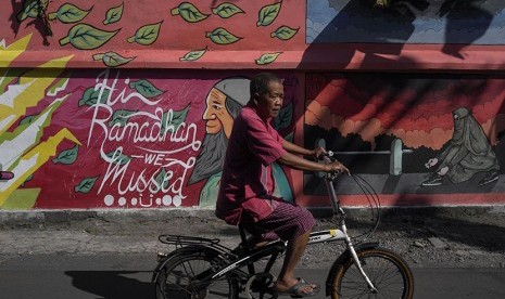 Warga melintas di depan mural bertema ramadan di kampung wisata batik Laweyan, Solo, Jawa Tengah, Rabu (24/5). 