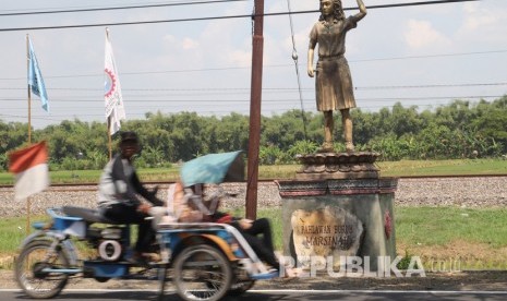 Warga melintas di depan patung Marsinah di Desa Nglundo, Nganjuk, Jawa Timur, Rabu (1/5). Menteri Pariwisata dan Ekonomi Kreatif, Sandiaga Salahuddin Uno mendorong pengembangan sektor pariwisata dan ekonomi kreatif (parekraf) di Kabupaten Nganjuk, Jawa Timur, sebagai upaya mempercepat kebangkitan sektor parekraf yang terdampak pandemi.