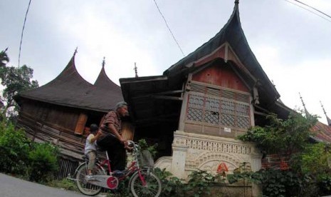 Warga melintas di depan rumah gadang di kampung 1000 rumah gadang di Nagari Koto Baru, Sumbar.  (Ilustrasi)