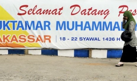 Warga melintas di depan spanduk penyambutan peserta Muktamar ke-47 Muhammadiyah di Kampus Universitas Muhammadiyah (Unismuh) Makassar, Sulawesi Selatan, Ahad  (26/7). 