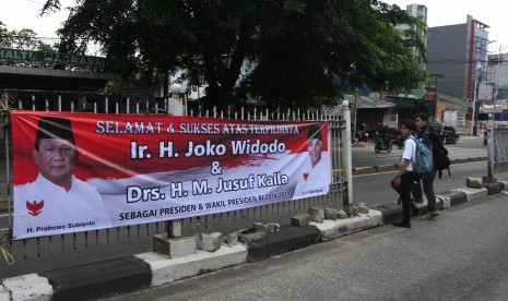 Warga melintas di depan spanduk ucapan selamat atas terpilihnya Jokowi-JK menjadi Presiden RI 2014-2019 dengan gambar Prabowo Subianto dan Hatta Rajasa di Jakarta, Rabu (23/7).