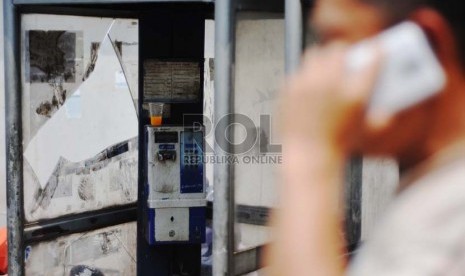 Warga melintas di depan telepon umum koin di kawasan Sudirman, Jakarta Selatan, Senin (13/10).(Republika/Raisan Al Farisi)