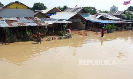 Warga melintas di depan tempat tinggalnya yang terendam banjir akibat meluapnya sungai Cisadane di kawasan Karawaci, Tangerang, Banten, Jumat (26/4/2019). 